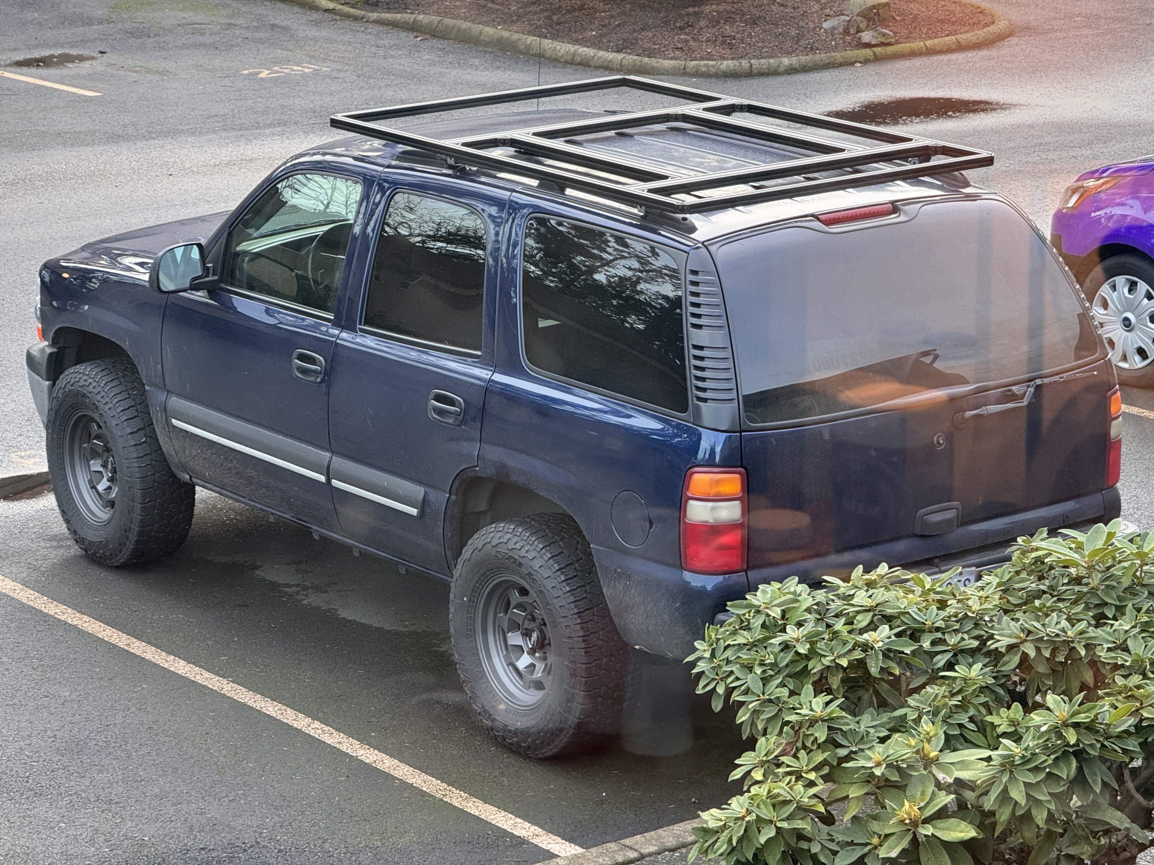 High-angle view of the blue Tahoe's custom aluminum extrusion roof platform mounted on low crossbars